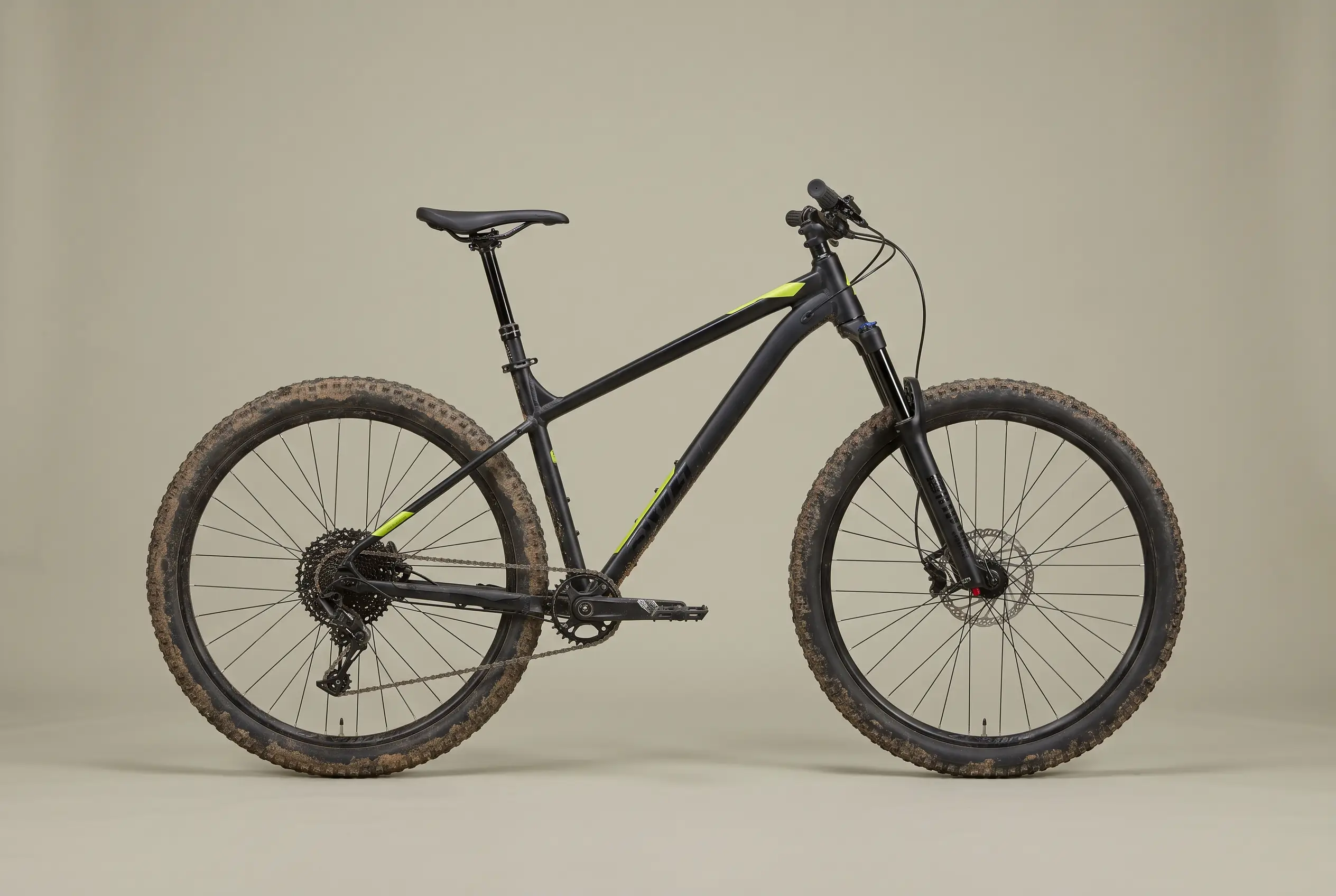 Matte black alloy hardtail with acid green decals and muddy knobbly tyres